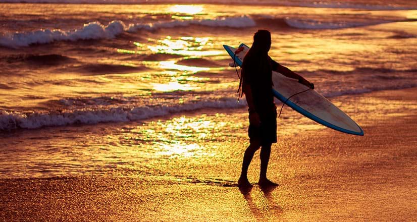 Surfeur sur la plage de Vichayito en regardant le coucher du soleil